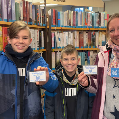 Raffael, Samuel und Kathrin freuen sich über die neuen Ausweise in der Stadtbücherei.