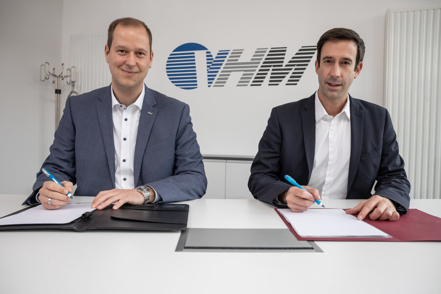 Marc Pf�tz, Gesch�ftsf�hrer der Versorgungsbetriebe Hann. M�nden GmbH (li.), und B�rgermeister Tobias Dannenberg sitzen an einem Tisch und unterzeichnen die Konzessionsvertr�ge. Im Hintergrund prangt das VHM-Logo an der Wand.