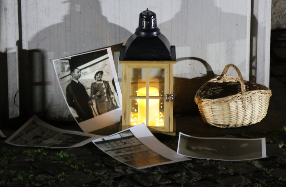 Eine Kerze erhellt an der Gedenkstele vor dem Rathaus im D�mmerlicht umherliegende Schwarz-Weiss-Fotos im stillen Gedenken an Holocaust-Opfer.