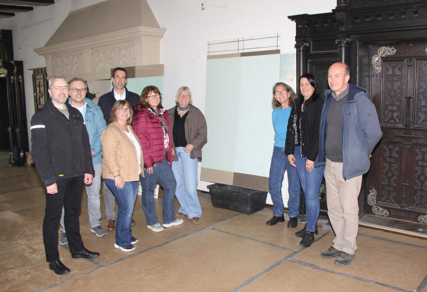 (V.li.) Burkhard Grote (Architekturb�ro pmp), Nico Harenkamp (Leiter Fachdienst Liegenschaften, Hochbau und Sanierung), B�rgermeister Tobias Dannenberg, Kerstin F�gner-Nehler, Nicole Herthum (beide Projektleitung und Mitarbeiterinnen des Fachdienstes Liegenschaften, Hochbau und Sanierung), Denkmalpflegerin Sabine Momm, Kerstin Hohm (Architekturb�ro pmp), Nicole Prediger (Leiterin Bereich Stadtentwicklung) sowie Kim Kappes (Landesamt f�r Denkmalpflege) vor einem Wandbereich, unter dem man die urspr�ngliche Farbgebung der Oberen Rathaushalle (T�rkis) freigelegt hat.