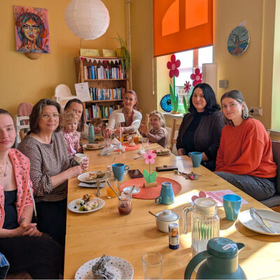 (V.re.) Madlien Wienberg, Melissa Castillo und Tina Krause (2.v.li.) mit einigen M&uuml;ttern und Kindern beim Fr&uuml;hst&uuml;ck im Familienzentrum.